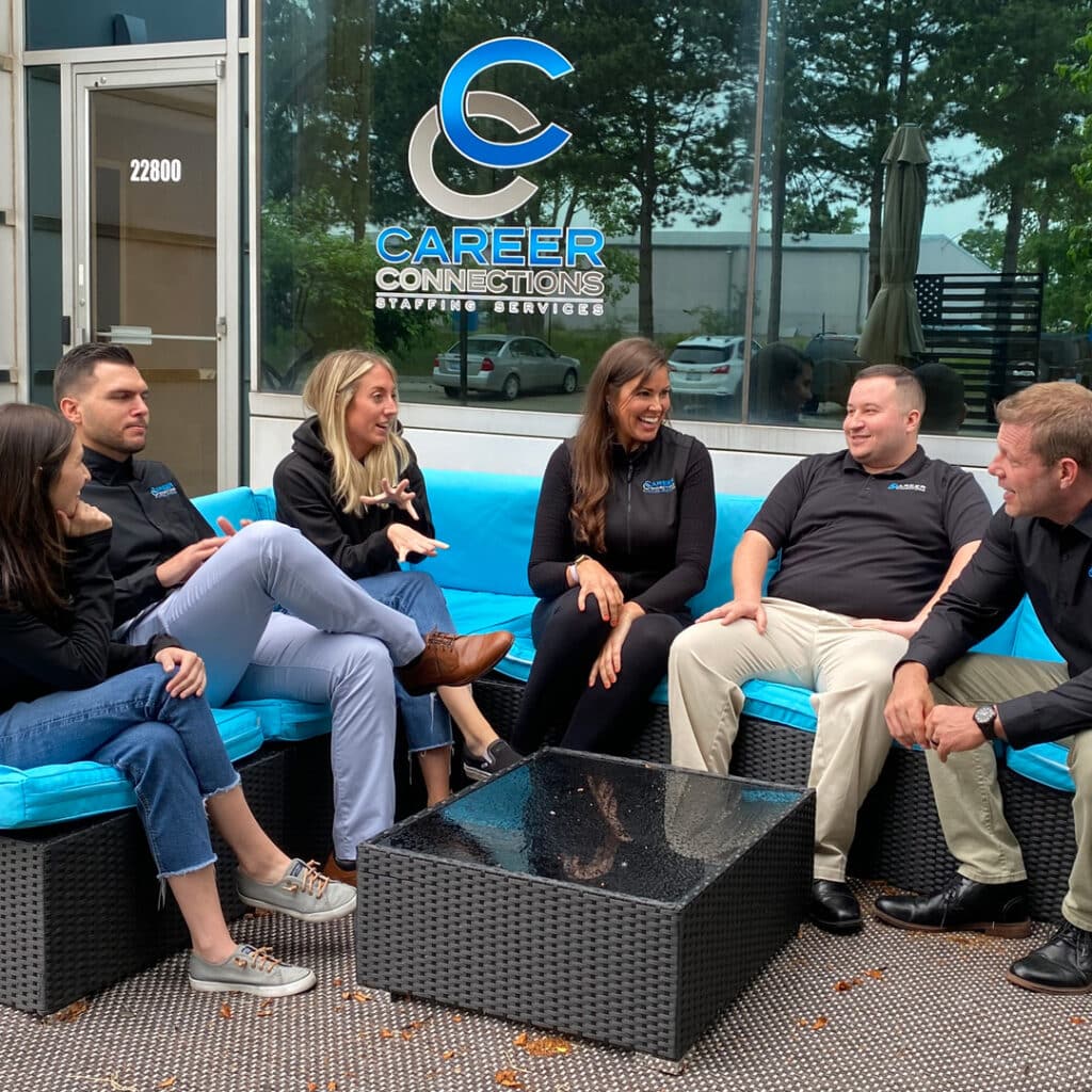 Career Connections team discussing staffing needs on a couch in their office.