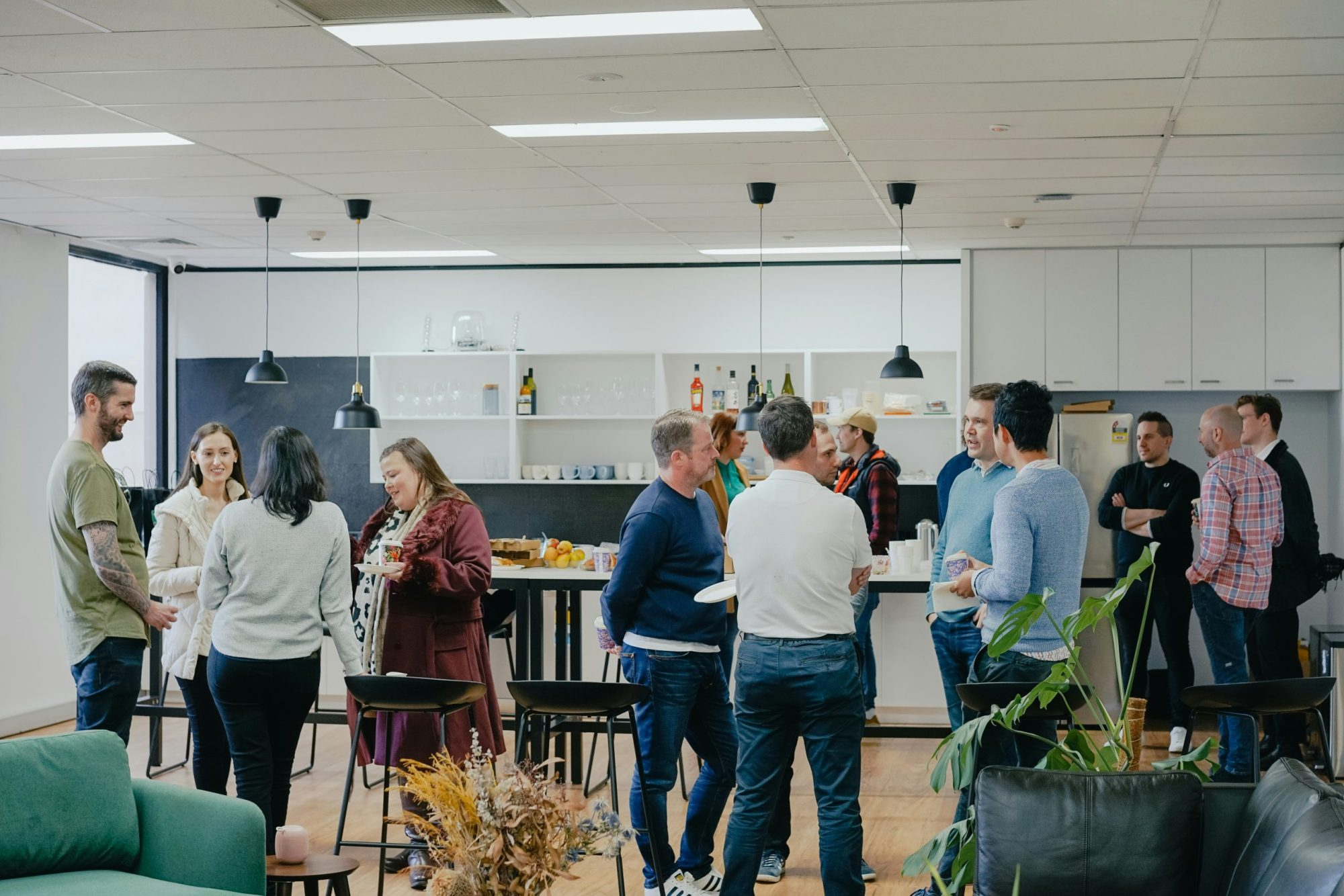 Employees gathered in a modern office break room discussing work, representing workplace collaboration and HR environment