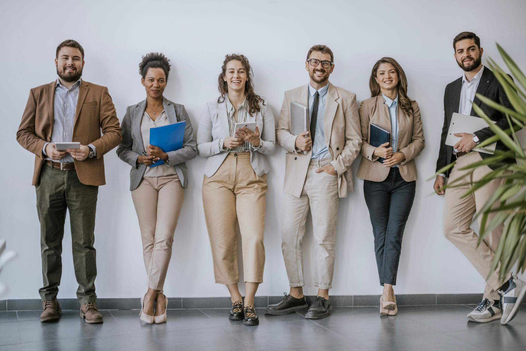 Diverse group of professional employees standing together in a modern office, representing a dependable and collaborative workforce.